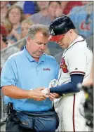  ?? John Bazemore / AP ?? Atlanta first baseman Freddie Freeman (5) has his hand examined by trainer Jim Lovell after he was hit by a pitch during a recent game.