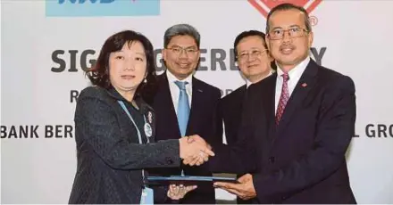  ??  ?? RHB Banking Group corporate banking head Wendy Ting Wei Ling (left) exchanging documents with Brunsfield Internatio­nal Group executive director Mohamad Hassan Zakaria at the signing of the agreement for the RHB financial supply chain platform in Kuala...