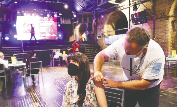  ?? HENRY NICHOLLS / REUTERS ?? A person receives a dose of the Pfizer Biontech vaccine at an NHS pop-up clinic on the dance floor of the Heaven nightclub in London, England.