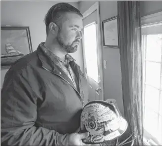  ?? MITCH MACDONALD/SALTWIRE NETWORK ?? John Holmes holds his old hardhat while looking out the window of his Murray Harbour home. Holmes wants to raise awareness about mental health and career re-training supports offered in P.E.I. to former oil patch workers struggling with the industry’s decline.