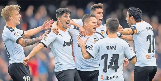  ??  ?? Wass, Soler, Gabriel Paulista, Gayà y Parejo abrazan a Kevin Gameiro tras lograr el delantero francés el primer gol del partido de Mestalla entre el Valencia y el Betis.