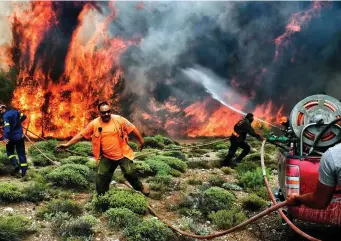  ??  ?? A woman wanders through the charred shells of burnt out cars as she searches for her dog near Athens; above, firefighte­rs and volunteers try to extinguish a blaze; below, people take refuge in the sea from the flames. Photos: Nikos Kalogeriko­s/Reuters; Angelos Tzortzini/AFP/Getty