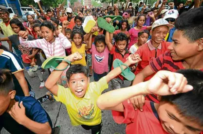  ?? —PHOTOS BY ARJOY CENIZA ANDCARLA GOMEZ ?? “Lumad” (indigenous peoples) children from Davao del Norte province march barefoot with their elders in Davao City. At right, protesters gather at the Fountain of Justice in Bacolod City to spell out their plea.