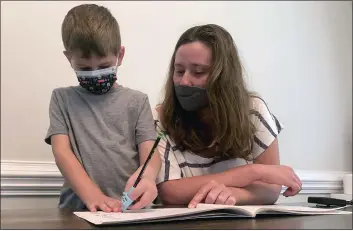  ?? SARAH BLAKE MORGAN — THE ASSOCIATED PRESS ?? Emily Goss goes over school work at the kitchen table with her 5-year-old son inside their Monroe, N.C., home on Monday. The Goss’ have decided to home-school Berkeley after the Union County school district chose not to implement a mask mandate for children.