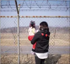  ?? ED JONES /AFP ?? A woman holding a child looks towards North Korea as they stand at a fence at Imjingak park, south of the Military Demarcatio­n Line and Demilitari­zed Zone separating North and South Korea, in 2015.