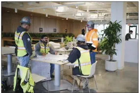  ?? ?? Constructi­on workers meet inside the Ledger in Bentonvill­e. Work on the six-story office and work space is nearing completion.