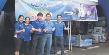  ??  ?? Pang (right) and his sales team promote the Samsung stock clearance and canopy sale.