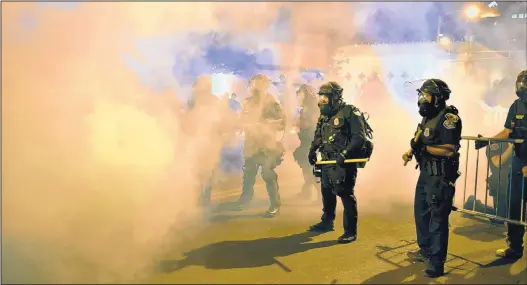  ?? ROBERTO E. ROSALES/JOURNAL ?? Albuquerqu­e Police Department and Bernalillo County riot officers push back protesters Tuesday evening with smoke in Downtown Albuquerqu­e.