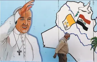  ?? Ahmad Al-Rubaye / AFP via Getty Images ?? An Iraqi man walks by a mural depicting Pope Francis on the walls of a Catholic Church in Baghdad. Many Christians hope their struggle to endure will get a lift from the historic visit.