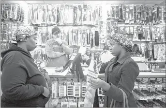  ?? YALONDA M. JAMES/THE COMMERCIAL APPEAL ?? Manager Raad Alyounis watches a s Makeasha Shor t (lef t) and her daughter, Mariah Wright, 16, negotiate a hair weave purcha se at Beauty & Beyond on Frayser Boulevard Thursday. Alyounis says hair thieves have struck his store t wice.