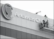  ?? NWA Democrat-Gazette/ANDY SHUPE ?? A worker passes the dot to the letter “I” to another worker Friday while assembling a sign from a gondola atop the nearly completed Arkansas Children’s Northwest hospital in Springdale. The hospital is expected to open next month.
