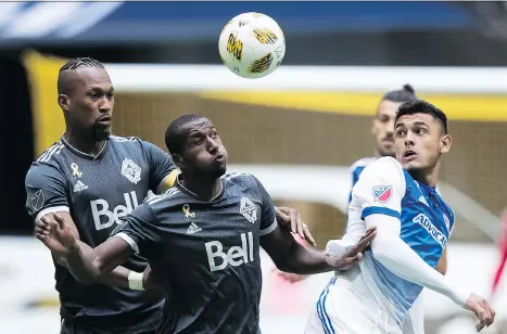  ?? DARRYL DYCK/THE CANADIAN PRESS ?? Vancouver Whitecaps player Ali Ghazal, front, and FC Dallas’ Cristian Colman, right, vie for the ball as Vancouver’s Kendall Waston backs his teammate up during Saturday’s deflating Whitecaps loss, a defeat that ultimately cost head coach Carl Robinson his job.
