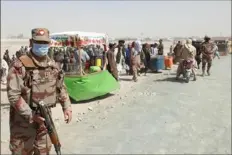  ?? Asghar Achakzai/AFP via Getty Images ?? An army soldier patrols as stranded people wait Saturday for the reopening of the border crossing point in Chaman, which was closed by the authoritie­s after the Taliban took control of the Afghan border town in a rapid offensive across the country.