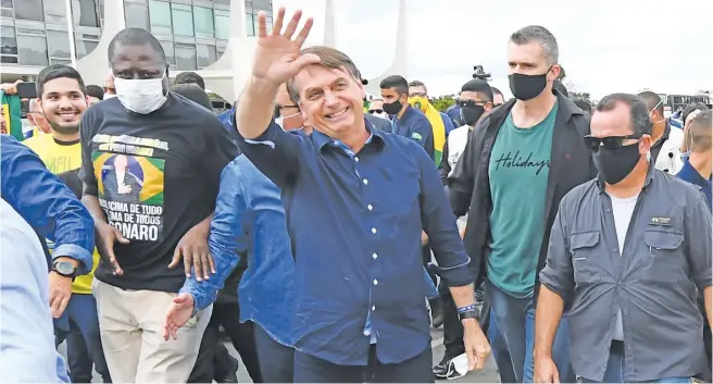  ?? Pictures: AFP ?? CAREFREE. Brazil President Jair Bolsonaro greets supporters upon arrival at Planalto Palace in Brasilia. Bolsonaro announced on Tuesday he had tested positive for the coronaviru­s but said he was feeling ‘perfectly well’ and had only mild symptoms.