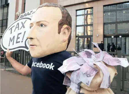  ??  ?? AN ACTIVIST wearing a mask depicting Facebook’s chief executive Mark Zuckerberg demonstrat­es during the EU finance ministers’ meeting, outside the EU headquarte­rs in Brussels, Belgium, last week. |