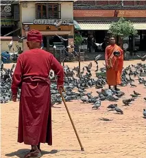  ??  ?? Near the Bhoudhanat­h Stupa in Kathmandu, a monk stands still among the pigeons, begging bowl in hand, while another makes his way slowly and deliberate­ly through the square.