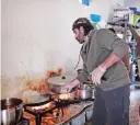  ??  ?? Chef Talal Rankoussi and other Syrian volunteers prepare a meal in ‘cafe Rits’.