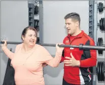  ?? JOE GIBBONS/THE TELEGRAM ?? Chris Hammond of Good Life Fitness instructs Cindy Barnes on the proper bar bell technique to use during a squat exercise as part of her new fitness regime.