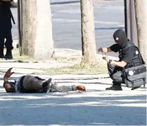  ??  ?? A member of the criminal police inspects the body of a suspect at the scene of an incident in which a car rammed a gendarmeri­e van on the Champs-Elysees Avenue in Paris on Monday. (Reuters)