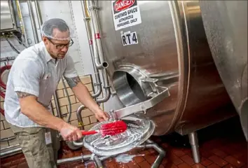  ??  ?? Matt Weyanet, a milk reviver, cleans a container for flavored milk.