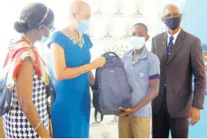  ?? PHOTO BY CARL GILCHRIST ?? Education Minister Fayval Williams hands a backpack to Shavon Thompson, a grade six student of Carron Hall Primary School, while Loretta Hamilton (left), school chairman, and Brenton Pinnock, principal, look on. School supplies were distribute­d by the organisati­on Reading Owls.