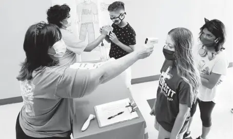  ?? LM OTERO/AP 2020 ?? Science teachers Ann Darby, left, and Rosa Herrera check in students before a summer STEM camp at a high school in Wylie, Texas.