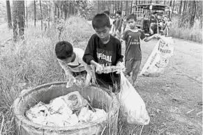  ?? — AFP ?? Students of Coconut School collecting discarded plastic water bottles and other recyclable scraps at Kirirom national park in Kampong Speu province.