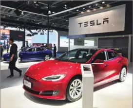  ?? LI FUSHENG / CHINA DAILY ?? A visitor walks past a Tesla Model S sedan at the second China Internatio­nal Import Expo held in Shanghai in November.