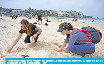  ?? — AFP ?? SYDNEY: Bondi cleanup day co-ordinator Julie Montedoro, 29 (left) and Isabel Young Perez, 32 (right) take part in a beach cleanup on Bondi beach in Sydney.