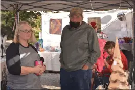  ?? PHOTOS BY JUSTIN COUCHOT — ENTERPRISE-RECORD ?? Shopper Holly Woods, stands alongside Lotus Metal Art co-owner Kreg Brawley on Sunday at the First Old Fashioned Christmas Fair hosted by the Meadows venue in Willows. Kreg, who’s company is based out of Durham, also sells wood carvings made from wood burned in the 2018 Camp Fire in Paradise.