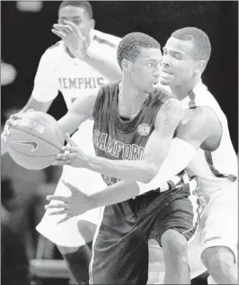  ?? MARK WEBER/THE COMMERCIAL APPEAL ?? Memphis’ Chris Crawford (right) applies defensive pressure to Samford’s Raijon Kelly (left) during second half action at FedEXForum Saturday night. The Tigers struggled before pulling out a 65-54 win over the Bulldogs.