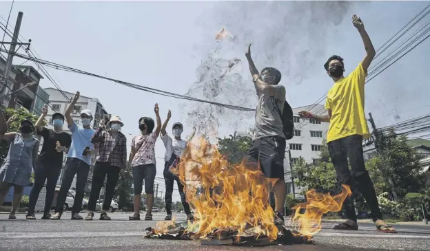  ??  ?? 0 Protesters make the three-finger salute as copies of the 2008 constituti­on are burnt during a demonstrat­ion against the military coup