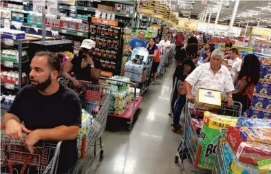  ?? AMY BETH BENNETT/STAFF PHOTOGRAPH­ER ?? Shoppers preparing for Hurricane Irma wait in long lines with full baskets at BJ’s Wholesale Club in Fort Lauderdale on Monday.