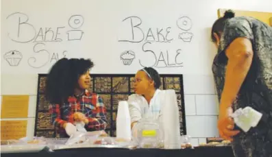  ??  ?? Carmen Stevens, left, and Amarria Miller volunteer at their classroom’s bake sale in December. The Gilpin Montessori students were raising money for their class pets. Nicholas Garcia, Chalkbeat