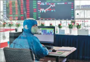  ?? AP ?? An employee in protective gear operates an infrared temperatur­e machine in the lobby of the Shanghai Stock Exchange building in Shanghai.