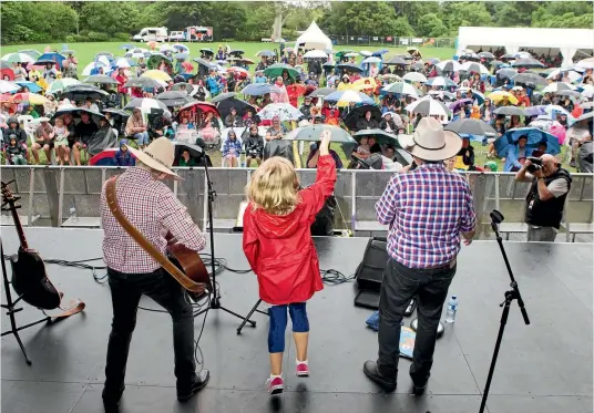  ?? PHOTO: TOM LEE/STUFF ?? Umbrellas were out in full force for the Topp Twins Kids Show at the Hamilton Gardens Arts Festival yesterday but Jools, left, and Lynda, right, made sure everyone had a great time.