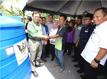  ?? — Photos by Chimon Upon ?? Abang Johari (left) presenting one of the water tanks to a villager from Kampung Tanjung Kelaso yesterday. Also seen are (from second left) Awla, Dr Rundi, Julaihi and Nancy.