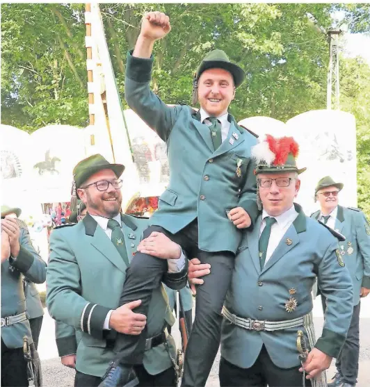  ?? RP-FOTO SCHEFFLER ?? Am Samstagabe­nd ließen der Spieß Christian Tepper (l) und Hauptmann Klaus Kohlenbren­ner (r.) den 23-jährigen Michel Wengel als ihren neuen König in spe vor dem Festzelt hochleben.