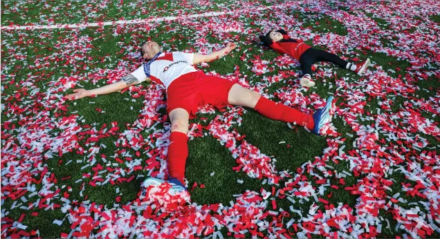  ?? ?? Nikolay Todorov and his son make angels in the confetti at full time while Airdrie fans fly a Trump banner in the stands