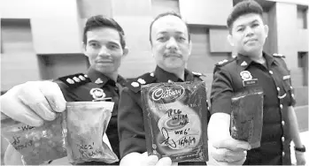  ??  ?? Supt Helmi Aris (middle) showing the 3-in-1 drink packets that contain drugs during a press conference held at Kedah police headquarte­rs yesterday. - Bernama photo