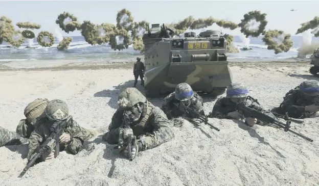  ?? PICTURE: KIM JUN-BUM/YONHAP ?? 0 US marines, left, and South Korean troops with blue headbands on their helmets take position after landing on a beach during a 2016 exercise