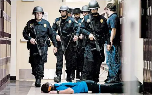  ?? RICHARD ALAN HANNON/AP ?? SWAT team walks down school hallway past a “victim” in 2008 during a safety this exercise.