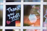  ?? Cloe Poisson / CTMirror.org ?? A health care worker at Kimberly Hall North in Windsor watches through a window as supporters show their appreciati­on to workers at the skilled nursing facility with a drive-through tribute in May 2020.