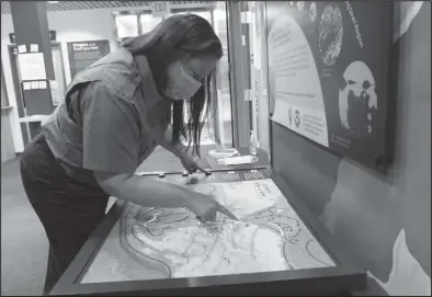  ?? Photos by Jenni Monet ?? MARINE DEBRIS EXHIBIT— Katie Cullen, Interpreta­tion and Education Program Manager at the Bering Land Bridge National Preserve explores the path of marine debris using an interactiv­e map as part of the One Big Ocean, One Big Issue exhibit currently featured at the Visitor Center.