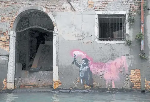  ?? ?? Una obra atribuida a Banksy, que representa a un niño migrante con chaleco salvavidas y una bengala, en una pared de Venecia, en mayo de 2019.