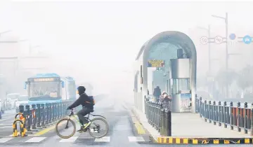  ??  ?? A cyclist crosses a smog-shrouded street in Lianyungan­g, eastern China’s Jiangsu province. — AFP photo