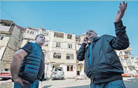  ??  ?? David Sargissian, left, the mayor of Stepanaker­t, surveys the damage to apartment blocks after the shelling