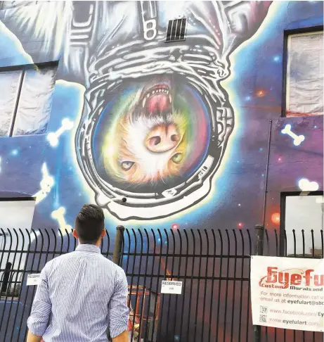  ?? Cameron Druecker ?? Montrose resident Barrett White studies the “Downtown Mars” mural painted by Sebastien Boileau on the side of the Texas Direct Auto building at 1301 Leeland. White parks near the building and says it now is “the best thing ever.”