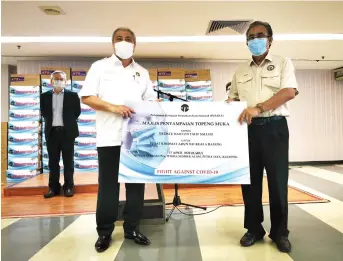  ?? By Roystein Emmor — Photo ?? Awang Tengah (left) symbolical­ly presents face masks to Len Talif who is also Kuala Rajang assemblyma­n.