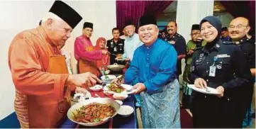  ??  ?? MOHD Khalil (kiri) menghidang­an masakan kepada Abdul Jalil pada sambutan Rumah Terbuka Aidilfitri PDRM di Dewan Serbaguna IPK Melaka, Bukit Beruang.